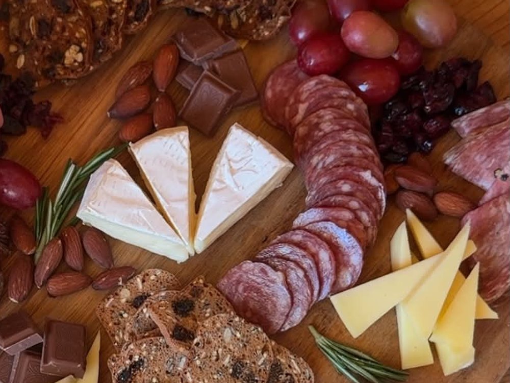 Charcuterie board with salami, brie, aged cheese, grapes, almonds, chocolate and crackers