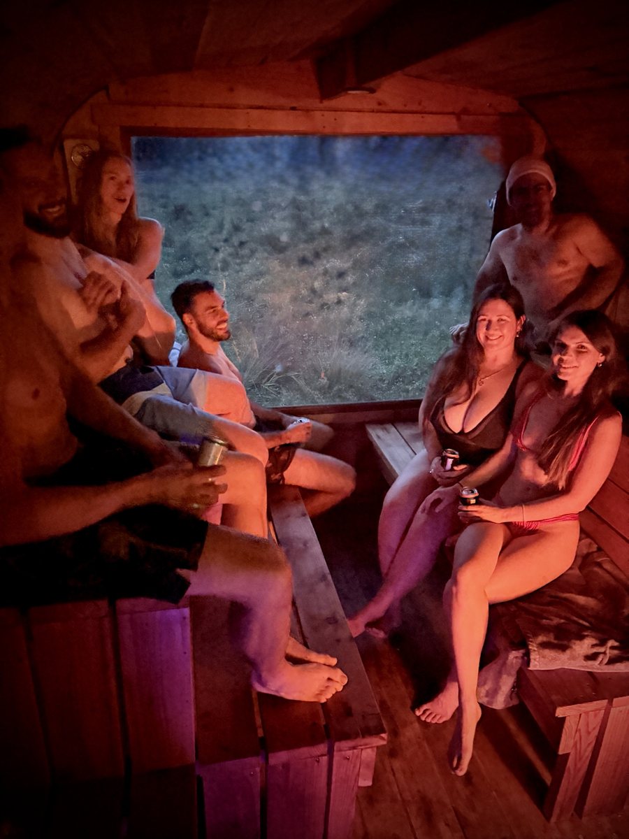 Group of friends relaxing inside the wood-fired mobile sauna at night