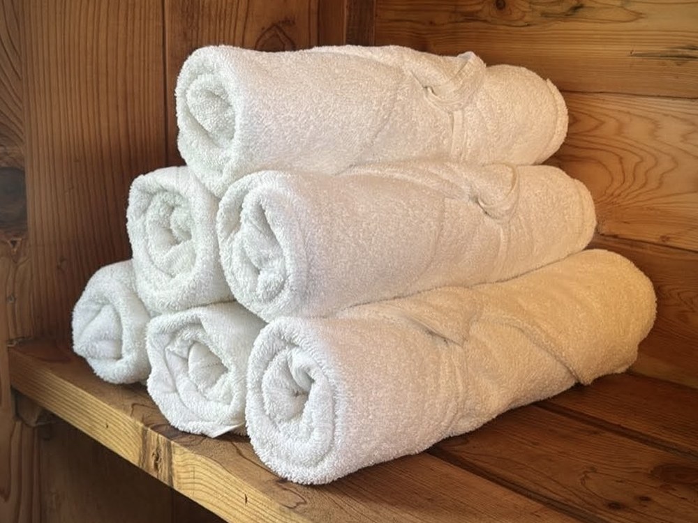 Stack of rolled white spa towels on a cedar sauna bench